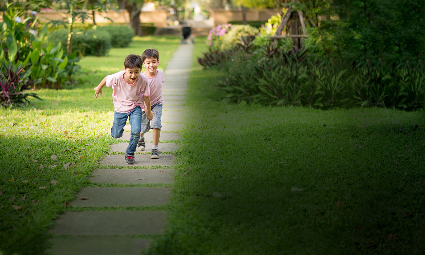 Two kids running through a neighborhood with smiles on their faces